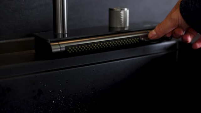 Close-up cinematic footage of a modern faucet with water flowing in a contemporary interior. The sequence shows the faucet being turned on, water running steadily, being turned off.