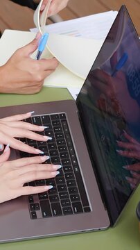 Business Colleagues Typing on Laptop and Reviewing Documents at Outdoor Table
