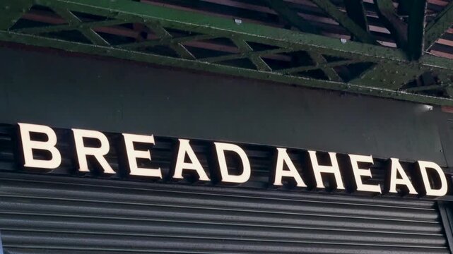 Bread Ahead bakery lettering sits above a closed shutter beneath a green metal canopy at London Bridge.
