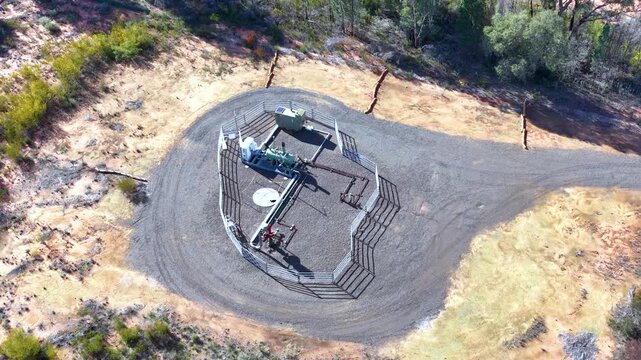 Aerial Overhead View of Fenced Gas Well Infrastructure in Rural Bushland