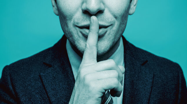 Man gesturing silence with finger on lips