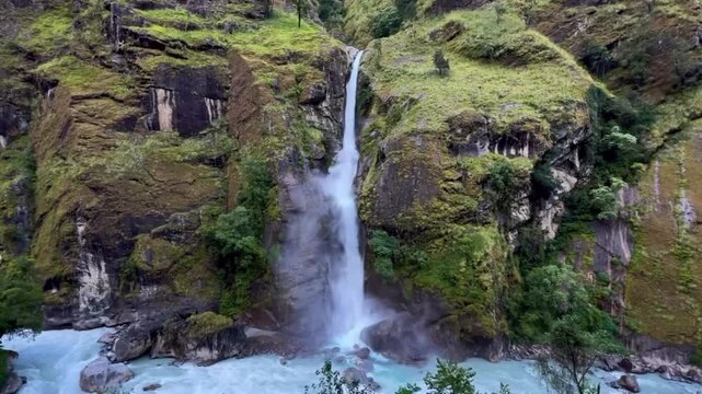 Waterfall cascading down a steep rocky cliff into a turquoise mountain river surrounded by lush greenery