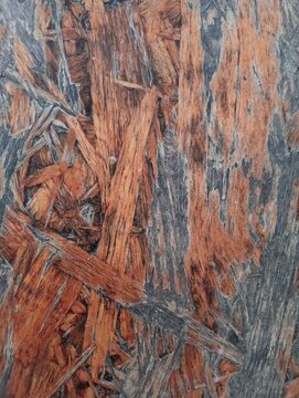 The surface texture of Oriented Strand Board (OSB) features an arrangement of flat wood chips and pieces pressed together with adhesive, creating a unique engineered wood material pattern for a backdr