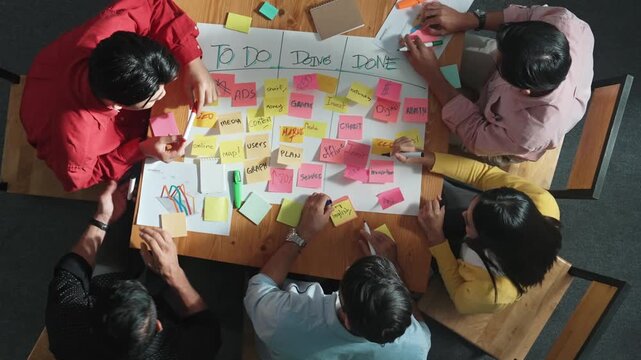Top view of people writing and making scrum task board while writing marketing and planning strategy at colorful sticky notes. Smart team manage work performance by using kanaban board. Convocation.