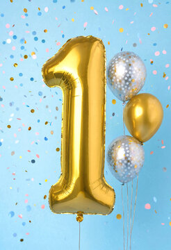 Golden number one balloon with festive confetti and shiny balloons