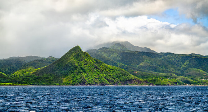 Lush green volcanic hills and mountains rising from the blue ocean along the scenic coastline of Dominica in the Caribbean