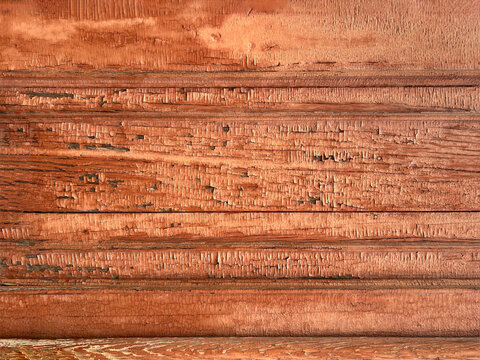 Close-up of heavily weathered reddish brown wood with cracked grain and rich natural texture.