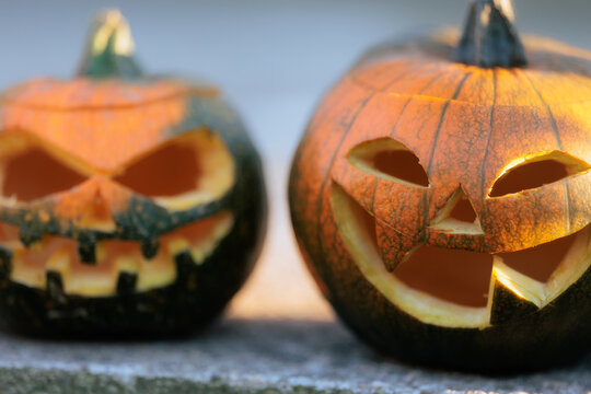 Two Carved Halloween Jack O Lantern Pumpkins With Spooky Scary Faces. Close up of two traditional orange pumpkins carved with creepy faces for Halloween