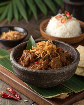 Photorealistic Indonesian beef rendang with glossy shredded beef toasted coconut fried shallots and pandan rice in clayware