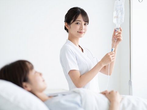 点滴のチューブを調節する優しい笑顔の女性看護師