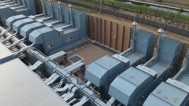 Large Data Center exterior site featuring rows of industrial cooling units and complex ventilation systems installed within a fenced perimeter for secure operations and temperature control.