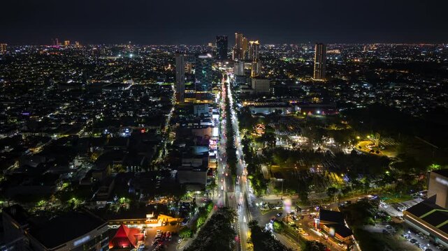 Aerial night timelapse of Surabaya, Indonesia, showing busy traffic along a major city road, illuminated buildings and an expansive urban skyline in East Java.