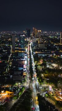 Aerial night timelapse of Surabaya, Indonesia, showing busy traffic along a major city road, illuminated buildings and an expansive urban skyline in East Java.