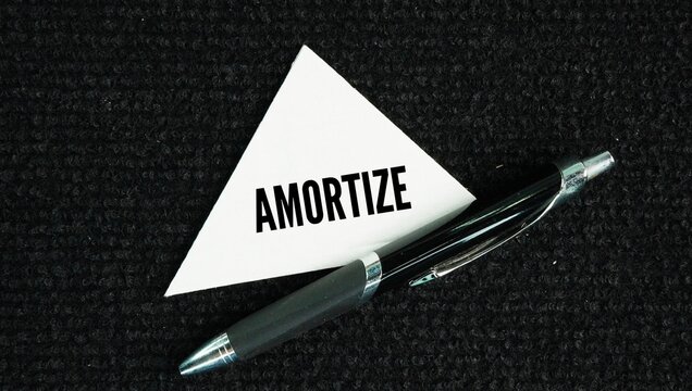 Pen and paper with the word Amortize - To gradually reduce and write off the cost of an asset in a company's accounts over a period of time
