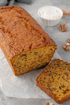 Carrot cake with cinnamon, walnuts and cream cheese frosting on a wooden board on a gray concrete background.