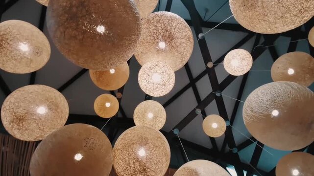 Handcrafted woven sphere pendant lights suspended from a timber-beamed ceiling in a contemporary interior