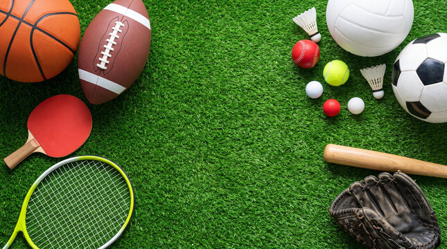 Various sports equipment including balls, rackets, and a baseball bat arranged on a green grass background
