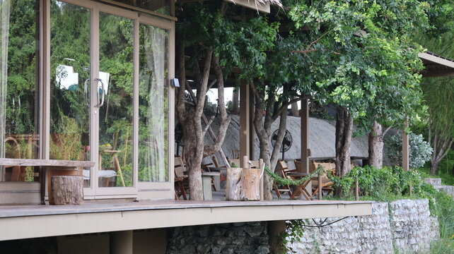 The image depicts an outdoor seating area adjacent to a building with glass sliding doors