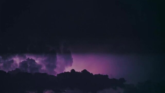 Dark storm clouds rolling across the night sky with a vivid purple lightning flash illuminating the cloud silhouette