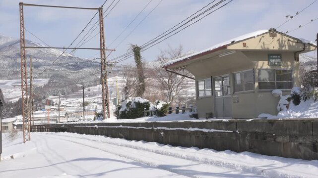 晴天の青空と深い雪に覆われたローカル線の駅のホームと待合室