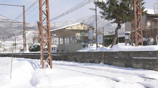 晴天の青空と深い雪に覆われたローカル線の駅のホームと待合室