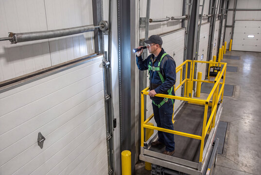 Worker on Scissor Lift Inspecting Warehouse Overhead Door