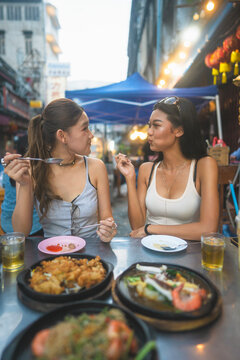  Two young asian adult women Gen Z foodie eating Thailand street food travel in Bangkok city at chinatown Yaowarat