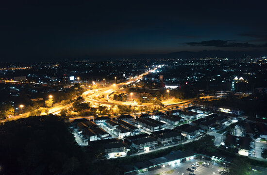 Aerial panorama of illuminated Don Chan intersection in Chiang Mai, Thailand, showing highway networks, evening traffic and urban growth for transport, infrastructure, real estate and travel concepts.
