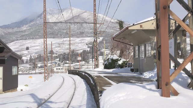 晴天の青空と深い雪に覆われたローカル線の駅のホームと待合室