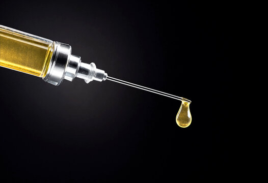 Closeup of golden liquid dripping from a glass dropper bottle in slow motion detail