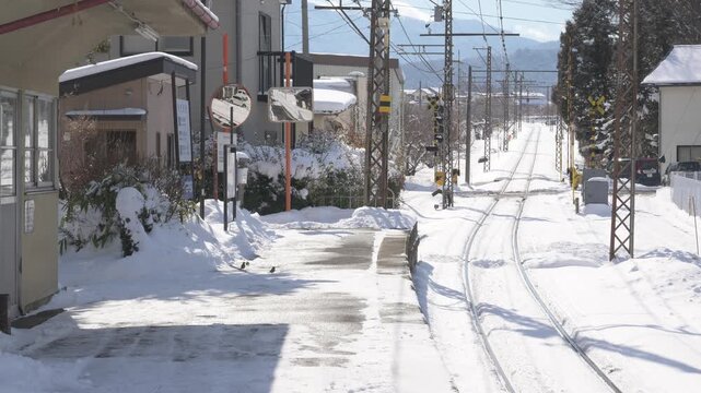 晴天の青空と深い雪に覆われたローカル線の駅のホームと待合室