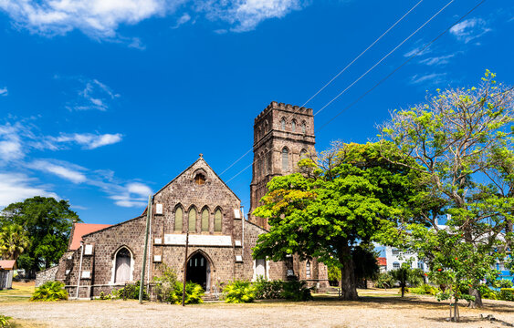 Exterior view of the historic St George Anglican Church built from volcanic stone under a blue sky in Basseterre, Saint Kitts.