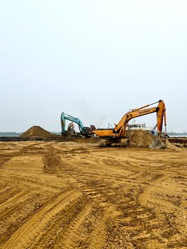 Sarawak, Malaysia - 24 September 2026: Tracked hydraulic excavators operating on an active sand processing depot alongside dirt mounds and construction infrastructure.