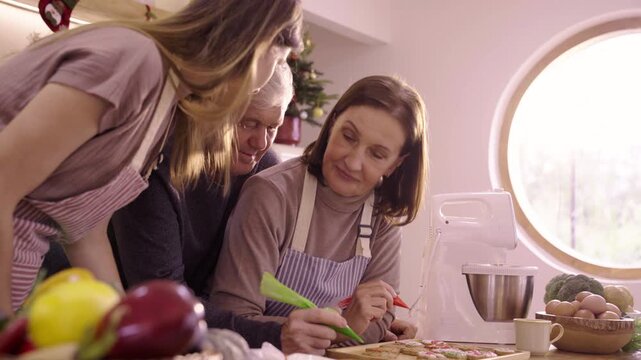 Caucasian family decorating gingerbread cookies in kitchen at home site