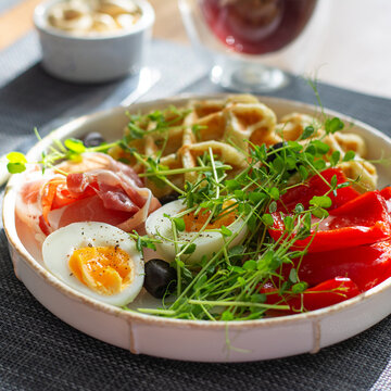 English breakfast. Boiled egg, jamon, waffles and green herbs.