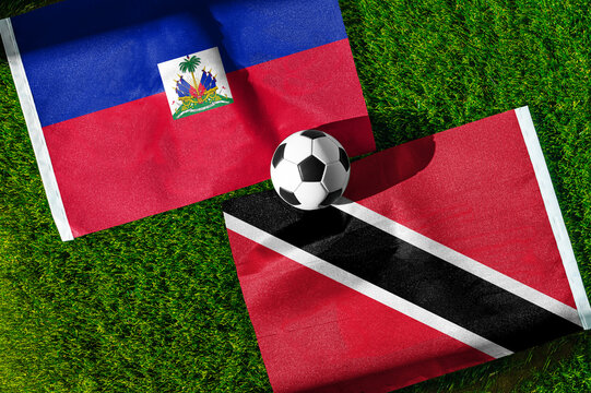 Haiti vs. Trinidad and Tobago football match. National flags on green grass with soccer ball in the middle. Football background for international match.