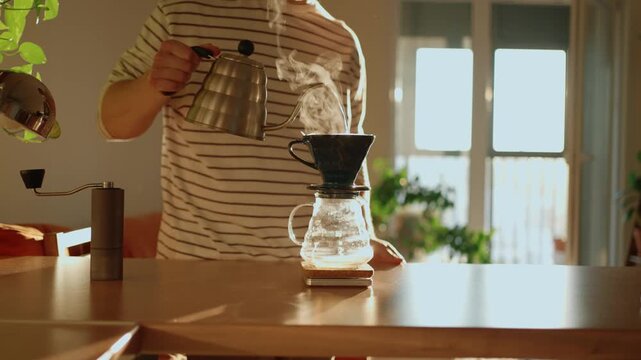 Young man meticulously brewing specialty coffee using the pour over method in his sunlit kitchen, skillfully pouring hot water from a gooseneck kettle over fresh grounds in a dripper