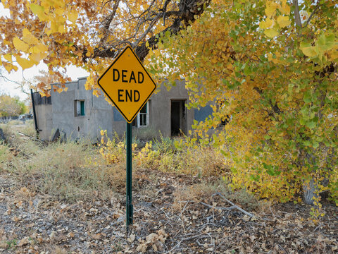 Dead end sign with autumn foliage at abandoned building