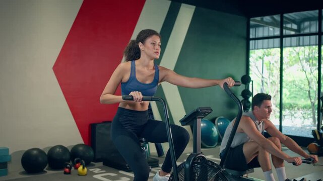 Young sportswoman exercising on elliptical cardio machine in fitness gym. 