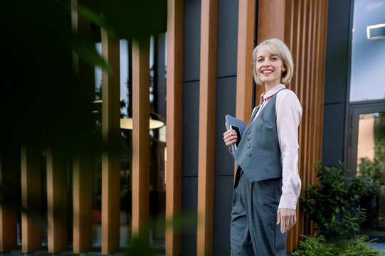 Businesswoman walking in modern office district confidently smiling