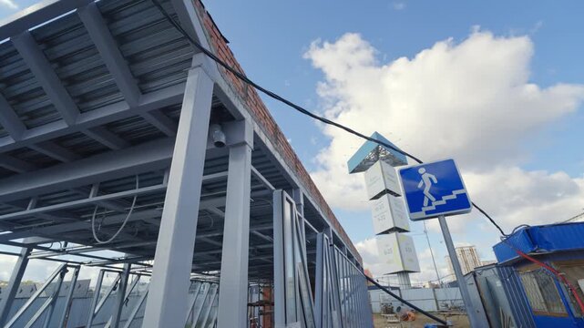 Pedestrian sign stands near roof scaffolding and temporary construction office. Street view displays ongoing infrastructure upgrade project