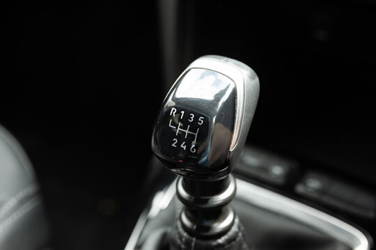 Close up view of six speed manual gear shift lever knob inside modern vehicle interior with selective focus