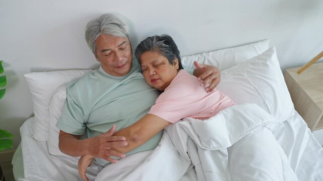 Asian sleepy senior elderly couple sleep on bed and hugging each other. 
