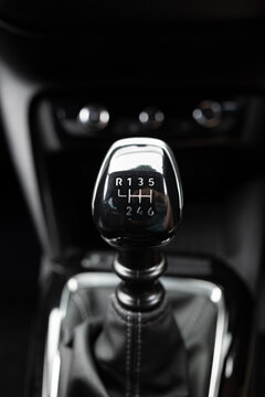 Six-speed manual gear shift knob with chrome trim and leather gaiter on center console inside modern vehicle