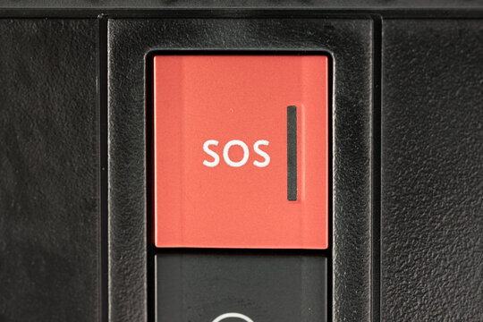 Red square emergency SOS call button on vehicle overhead plastic console panel inside modern car cabin
