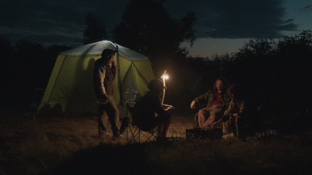 Group of men camping in the wild and gather near the bonfire and talk with each other. Fishermen camping and talk stories at night