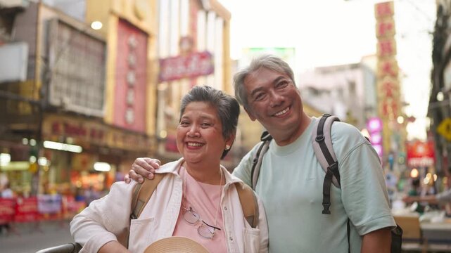 Portrait of Asian senior couple smiling while exploring city outdoors. 