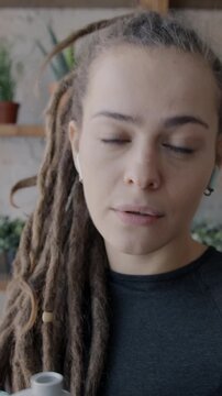 Portrait of joyful young sportswoman making online video call talking and drinking water from bottle looking at camera at home. Sports and communication concept.