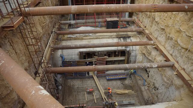 Underground trench features multi level steel struts and soil walls. Excavation site highlights intensive engineering foundation phase