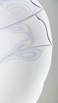 Microscopic timelapse of drying chicken egg white protein droplet cracking with thin film light interference rainbow patterns. Natural light refraction phenomenon, not digital artifact or banding